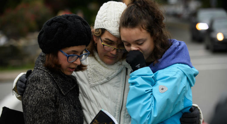 Tammy Hepps, Kate Rothstein and her daughter, Simone Rothstein, 16, pray from a prayerbook a block away from the site of a mass shooting at the Tree of Life Synagogue in the Squirrel Hill neighborhood on October 27, 2018 in Pittsburgh, Pennsylvania.