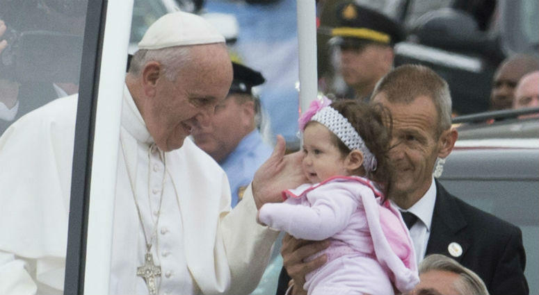 Pope Francis touches a toddler after kissing her at a stop in Logan Square on the Benjamin Franklin Parkway in Philadelphia on Sunday, Sept. 27, 2015. Pope Francis