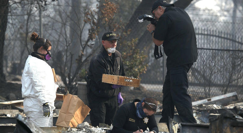 A sheriff deputy photographs a tray with human remains that were recovered from a home that was destroyed by the Camp Fire on November 16, 2018 in Paradise, California.