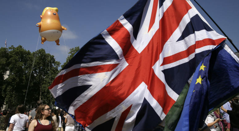 An EU and a British union flag are displayed in front of a six-meter high cartoon baby blimp of U.S. President Donald Trump, as it is flown as a protest against his visit, in Parliament Square in London, England, Friday, July 13, 2018. An EU and a British union flag are displayed in front of a six-meter high cartoon baby blimp of U.S. President Donald Trump, as it is flown as a protest against his visit, in Parliament Square in London, England, Friday, July 13, 2018.