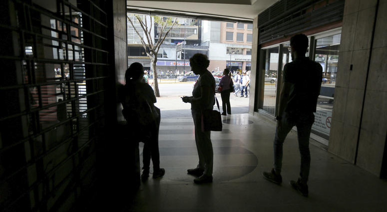 People wait inside a darkened office building during a power outage in Caracas, Venezuela, Monday, March 25, 2019. People wait inside a darkened office building during a power outage in Caracas, Venezuela, Monday, March 25, 2019.