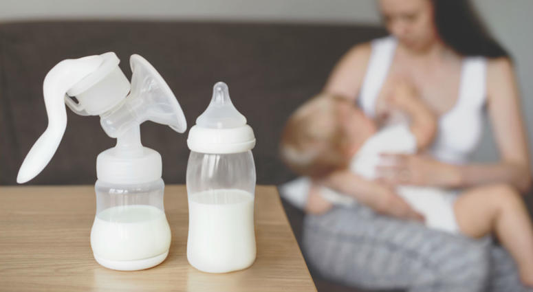 Bottle and breast pump with breast milk on the background of mother holding in her hands and breastfeeding baby Bottle and breast pump with breast milk on the background of mother holding in her hands and breastfeeding baby