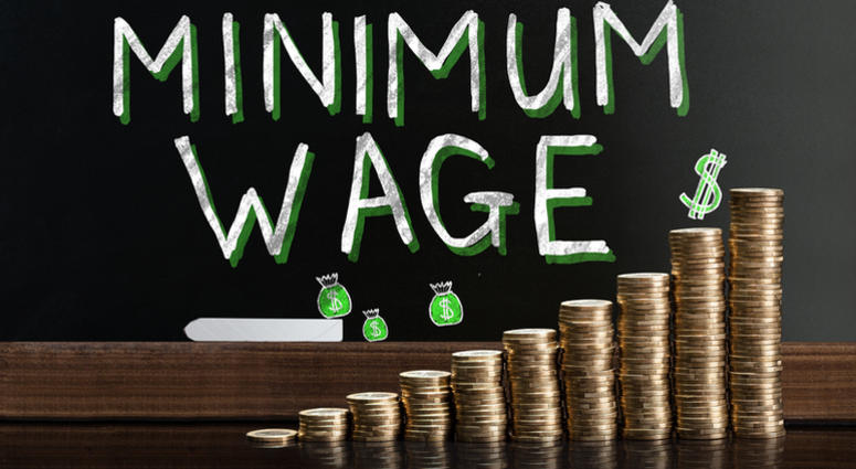 Minimum Wage At Blackboard Behind Stacked Coins minimum wage