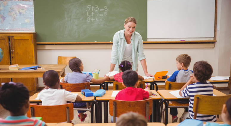 Teacher talking to the young pupils in classroom at the elementary school. Classroom