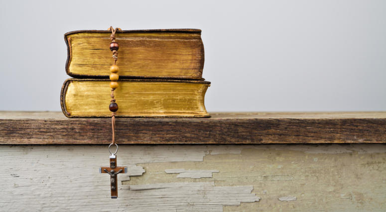 The books of Catholic Church liturgy and rosary beads on the wooden table The books of Catholic Church liturgy and rosary beads on the wooden table