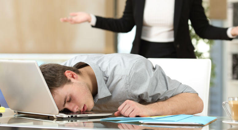 Employee sleeping with the face over the laptop with his angry boss watching back at office. Sleeping on the job