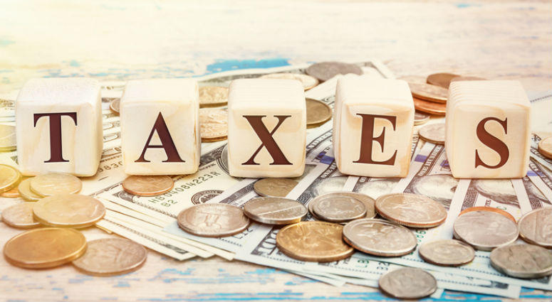 Word "TAXES" written with wooden cubes and money on the old table. taxes
