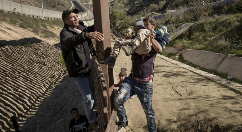 In this Saturday, Dec. 29, 2018, file photo, a man passes a Mexican migrant baby to her mother after they jump the border fence to get to the U.S. side to San Diego, from Tijuana, Mexico. In this Saturday, Dec. 29, 2018, file photo, a man passes a Mexican migrant baby to her mother after they jump the border fence to get to the U.S. side to San Diego, from Tijuana, Mexico.