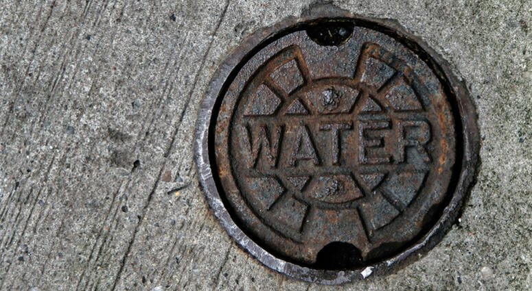 A water main manhole cover on pavement. A water main manhole cover on pavement.