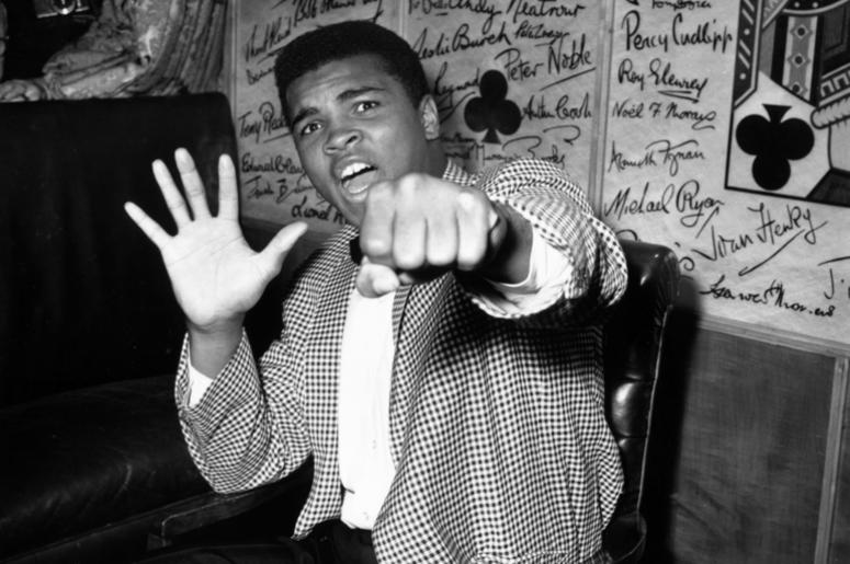 Cassius Clay a.k.a. Muhammad Ali 27th May 1963: Supremely confident American boxer Cassius Clay holds up five fingers in a prediction of how many rounds it will take him to knock out British boxer Henry Cooper. (Photo by Kent Gavin/Keystone/Getty Images)