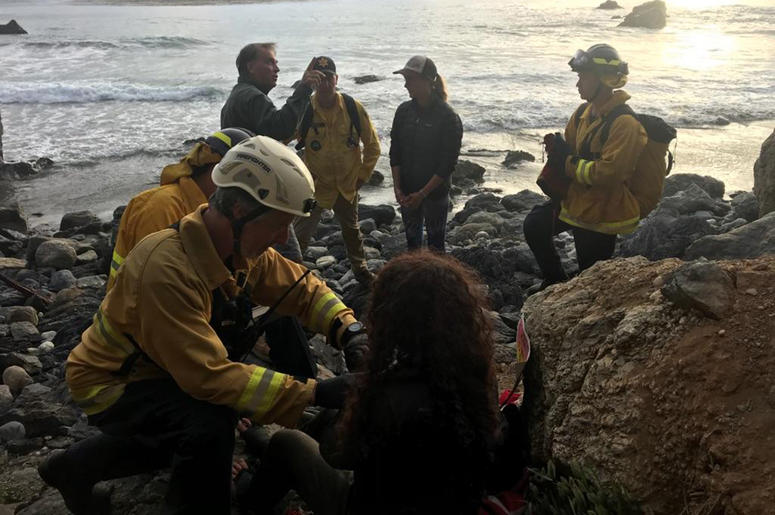 9ccedf81f07045b49408cd909a995261 In this Friday, July 13, 2018, photo posted on the Monterey County, Calif., Sheriff's Office Twitter feed, authorities tend to Angela Hernandez, foreground center, after she was rescued, in Morro Bay, Calif. Authorities say a couple on a camping trip came