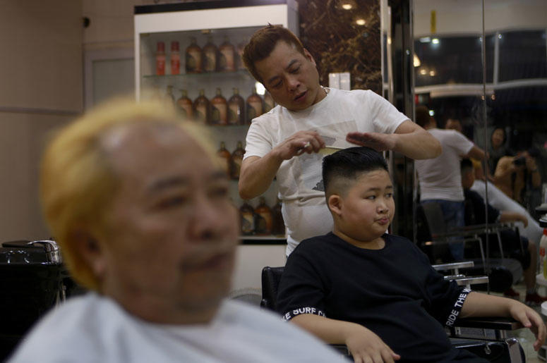 Le Phuc Hai, 66, left, and To Gia Huy, 9, have Trump and Kim haircuts in Hanoi, Vietnam, on Tuesday, Feb. 19, 2019. U.S. President Donald Trump and North Korean leader Kim Jong Un have become the latest style icons in Hanoi, a week before their second sum