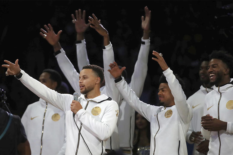 AP18290127159063 Golden State Warriors' Stephen Curry, left, speaks to fans during an awards ceremony to recognize the team's NBA championship prior to a basketball game against the Oklahoma City Thunder, Tuesday, Oct. 16, 2018, in Oakland, Calif. (AP Photo/Ben Margot)