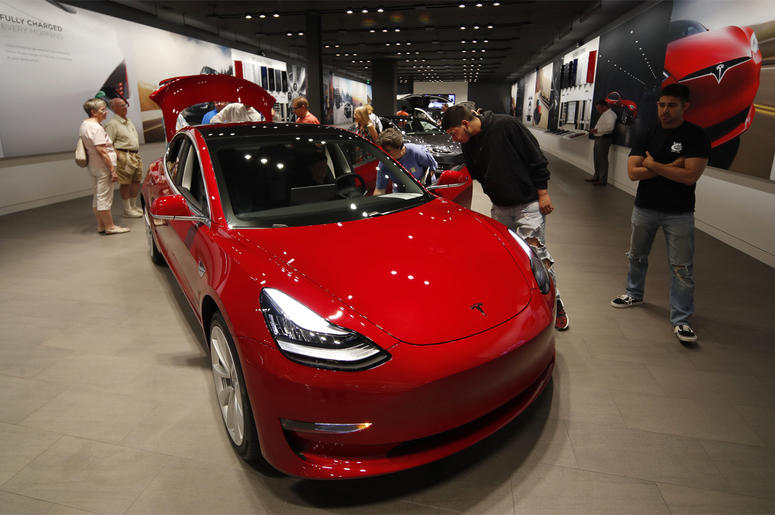 AP19070499871613 In this July 6, 2018, file photo prospective customers confer with sales associates as a Model 3 sits on display in a Tesla showroom in the Cherry Creek Mall in Denver. (AP Photo/David Zalubowski, File)