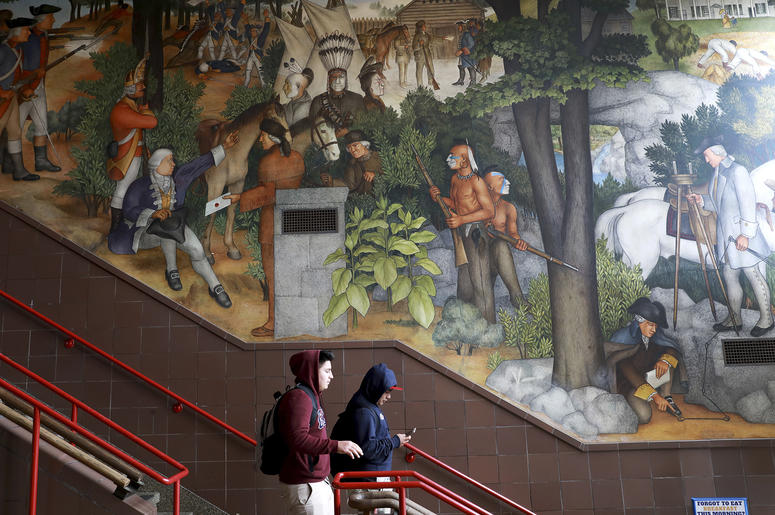 AP19178748483141 In this photo taken April 3, 2019, a pair of students walk past a historic mural that includes slaves and a dead Native American at George Washington High School in San Francisco. (Yalonda M. James/San Francisco Chronicle via AP)