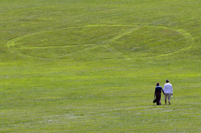 Carol Laura, left, and George Acquaire walk barefoot to a peace sign mowed in the grass at the site of the 1969 Woodstock Music and Arts Fair, Wednesday, July 24, 2019 in Bethel, N.Y. Woodstock will be celebrated on its 50th anniversary, but it won't be y