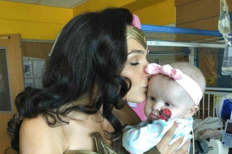 This image released by Kelly Swink Sahady shows Gal Gadot, dressed as Wonder Woman holding Sahady's daughter Karalyne during a visit to Inova Children's Hospital in Falls Church, Va. DO NOT USE