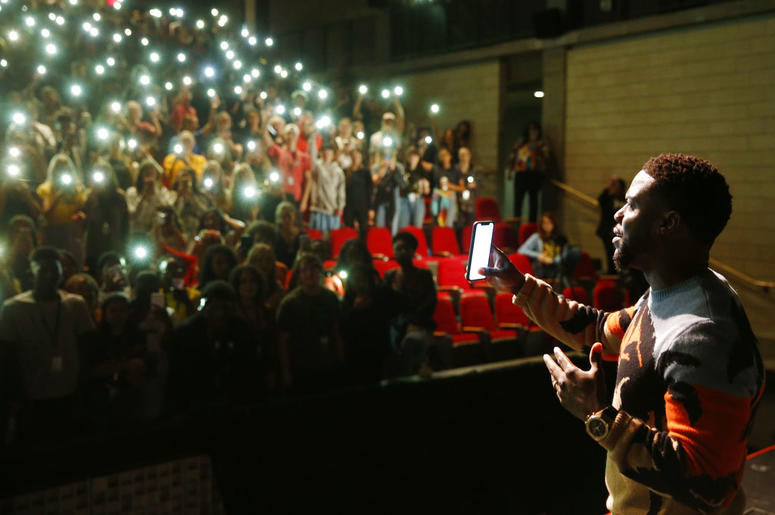 In this Sept. 12, 2018 photo, comedian and actor Kevin Hart films himself from a cellphone after talking to the students at Booker T. Washington High School in Dallas. DO NOT USE