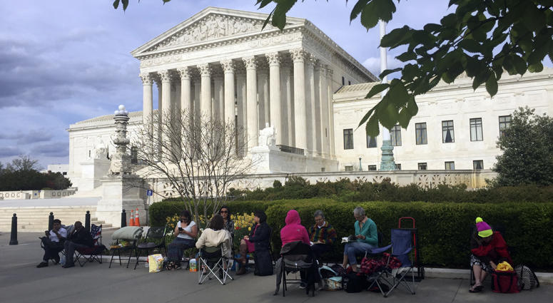 In this April 23, 2018, photo, people wait in line outside the Supreme Court in Washington, to be in the gallery when the court hears arguments in on April 25, over President Donald Trump’s ban on travelers from several mostly Muslim countries. Supreme Court