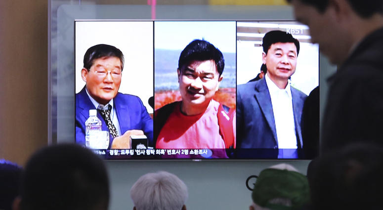 In this May 3, 2018 photo, people watch a TV news report on screen, showing portraits of three Americans, Kim Dong Chul, left, Tony Kim and Kim Hak Song, right, detained in the North Korea, at the Seoul Railway Station in Seoul, South Korea. North Korean Detainees Released