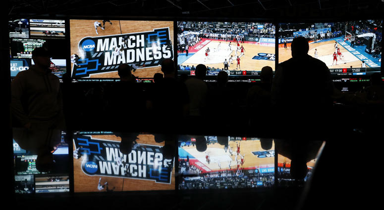 In this March 15, 2018 photo, people watch coverage of the first round of the NCAA college basketball tournament at the Westgate Superbook sports book in Las Vegas.