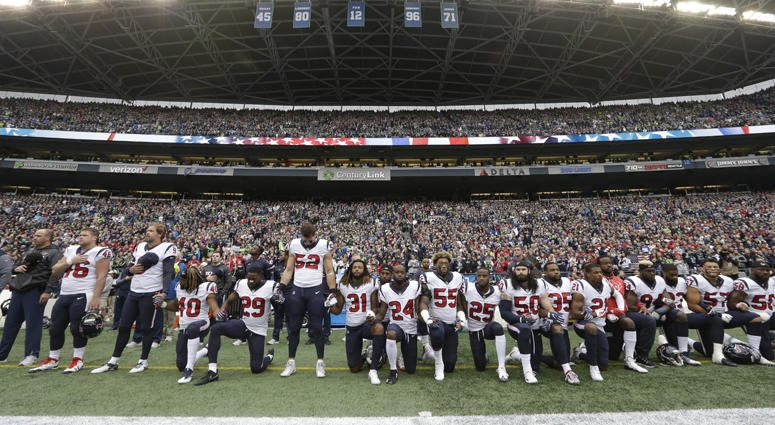 In this Oct. 29, 2017, file photo, Houston Texans players kneel and stand during the singing of the national anthem before an NFL football game against the Seattle Seahawks, in Seattle. NFL National Anthem Protest