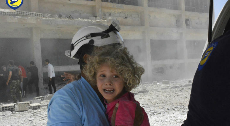 A Syrian White Helmet carrying a child after an airstrike. White Helmets AP