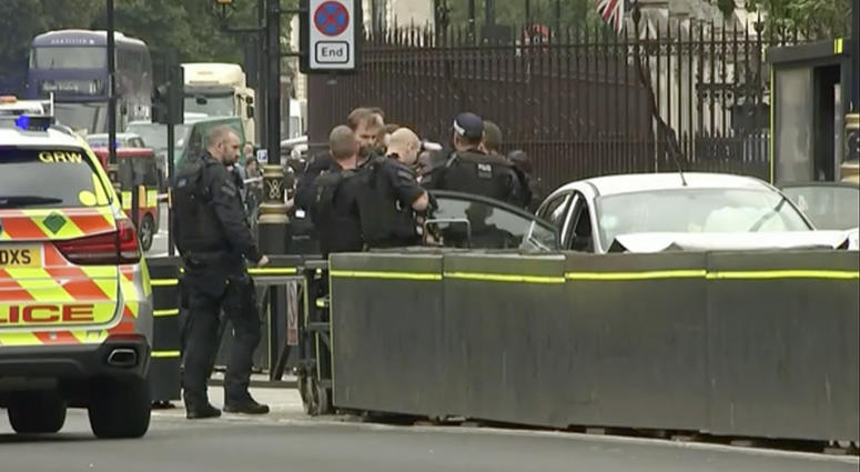 In this frame grab taken Tuesday, Aug. 14, 2018 armed police train their weapons on a car crashed into security barriers outside the Houses of Parliament stands to the right of a bus in London. London crash
