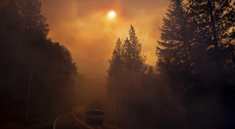 A vehicle drives through smoke from a wildfire near Pulga, Calif., Sunday, Nov. 11, 2018. California Wildfires