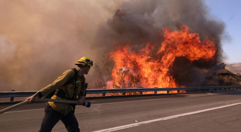 A firefighter battles a fire along the Ronald Reagan (118) Freeway in Simi Valley, Calif., Monday, Nov. 12, 2018. Southern Cali Fire
