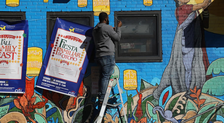 A building supervisor, who declined to identify himself, hangs banners on the front of the Jacob Riis Settlement House, Friday, Nov. 16, 2018, in New York. Amazon LIC Headquarters