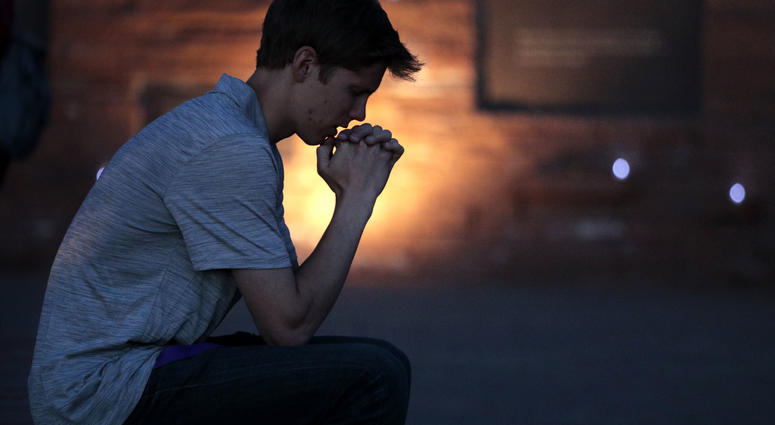 Spencer Greenlee, 17, a senior at Columbine High School prays at the Columbine Memorial during a candle light vigil held on April 19, 2019 in Littleton, Colorado. Columbine anniversary