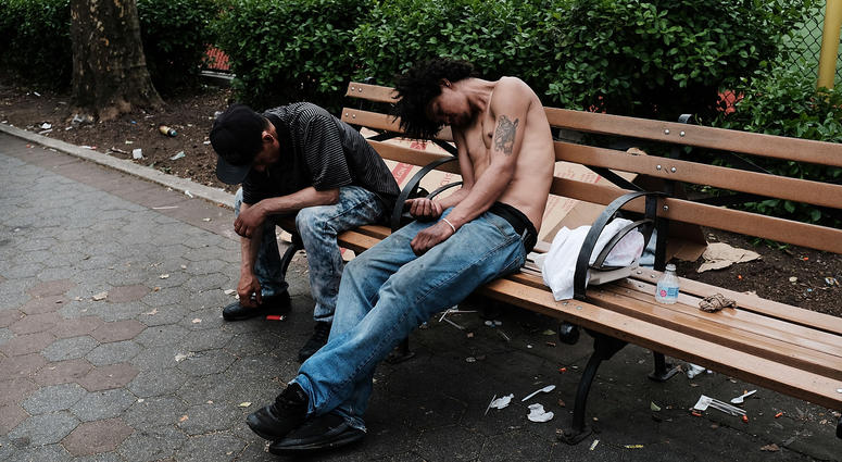 Men sit passed out in a park where heroin users gather to shoot up in the Bronx on May 4, 2018 in New York City. Heroin users