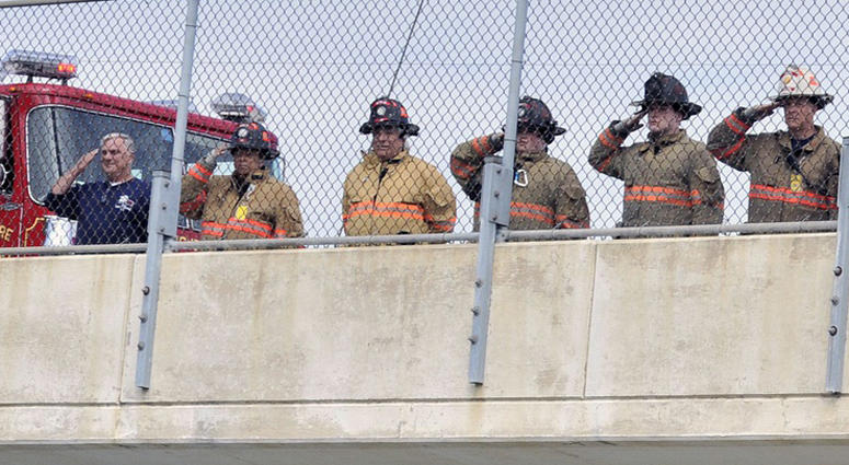 Dover and Lewes firemen salute as the procession carrying the body of New York city fireman and Marine S/Sgt. Christopher Slutman travels north on Rt. 1 towards New York City Firefighters Honor Fallen Marine