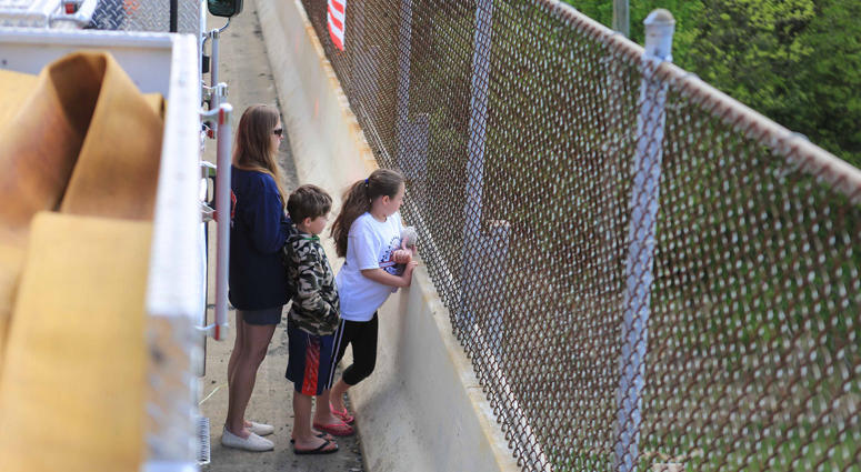 A mother and her two young children stand on the Kirkwood St. Georges Rd. overpass to showed support as the motorcade carrying the body of Marine Staff Sgt. Christopher Slutman passed underneath them on Rt. 1. Firefighters Honor Fallen Marine