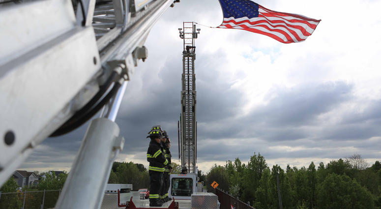 A firefighter from Aetna Hose Ladder Company in Newark stand on top of a firetruck on the Kirkwood St. Georges Rd. overpass as they showed support for the motorcade carrying the body of Marine Staff Sgt. Christopher Slutman, who was killed in a roadside b Firefighters Honor Fallen Marine