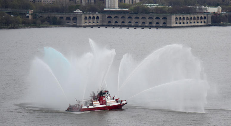 An FDNY boat shoots water into the air after the hearse carrying U.S. Marine Staff Sgt. and FNDY Firefighter Christopher Slutman crossed over the Geo Firefighters Honor Fallen Marine