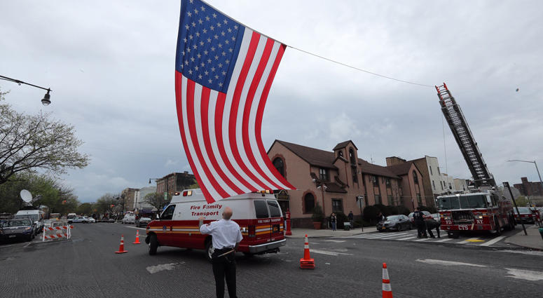 Firefighters stretch an American flag across Morris Park Avenue in the Bronx outside the Joseph Lucchese Funeral Home Monday as they wait for the body of NYFD member and U.S. Marine Christopher Slutman to arrive. Firefighters Honor Fallen Marine