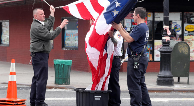 Members of the New York City Fire Department unfurl an American Flag outside the Joseph Lucchese Funeral Home in the Bronx April 21, 2019 as they wait for the body of FDNY member and U.S. Marine Christopher Slutman to arrive. Firefighters Honor Fallen Marine
