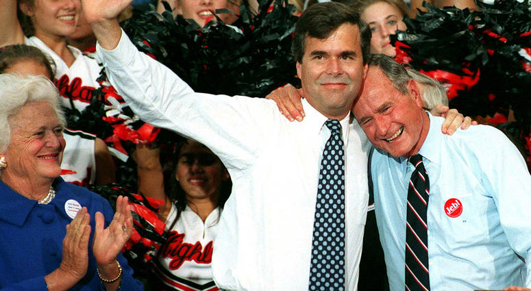 Former U.S. president George Bush embraces his son, Jeb, as Barbara Bush applauds during a rally in downtown Orlando, Florida, October 10, 1994. George H.W. Bush