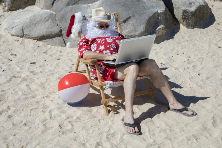 Santa Claus working on beach with laptop computer Santa Claus working on beach with laptop computer