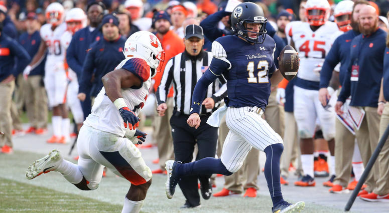 Nov 17, 2018; New York, NY, USA; Notre Dame Fighting Irish quarterback Ian Book (12) runs with the ball as Syracuse Orange linebacker Shyheim Cullen (24) defends during the second quarter at Yankee Stadium. Mandatory Credit: Rich Barnes-USA TODAY Sports Nov 17, 2018; New York, NY, USA; Notre Dame Fighting Irish quarterback Ian Book (12) runs with the ball as Syracuse Orange linebacker Shyheim Cullen (24) defends during the second quarter at Yankee Stadium. Mandatory Credit: Rich Barnes-USA TODAY Sports