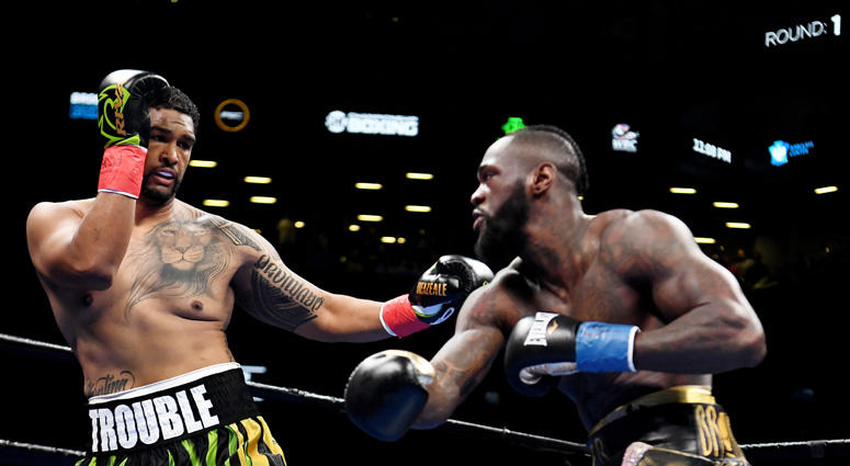 Deontay Wilder (bronze trunks) trades punches with Dominic Breazeale (green trunks) in the first round of a world heavyweight championship boxing match at Barclays Center. Deontay Wilder (bronze trunks) trades punches with Dominic Breazeale (green trunks) in the first round of a world heavyweight championship boxing match at Barclays Center.