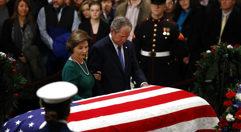 Former President George W. Bush and former first lady Laura Bush pause in front of the flag-draped casket of former President George H.W. Bush as he lies in state in the Capitol's Rotunda in Washington, Tuesday, Dec. 4, 2018.(AP Photo/Patrick Semansky)