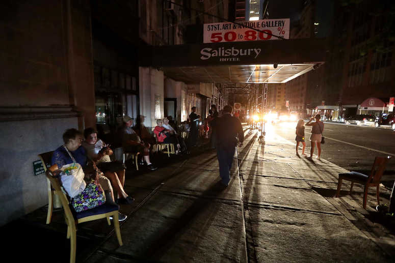 People sit outside a midtown hotel after a power outage left large parts of the West Side of Manhattan without power July 13, 2019. NYC power outage