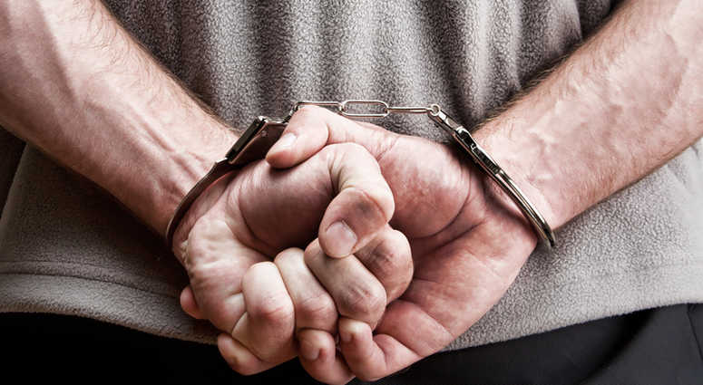 Criminal hands locked in handcuffs. Close-up view Criminal hands locked in handcuffs. Close-up view