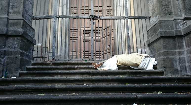 A homeless person sleeps on the steps of a church. A homeless person sleeps on the steps of a church.