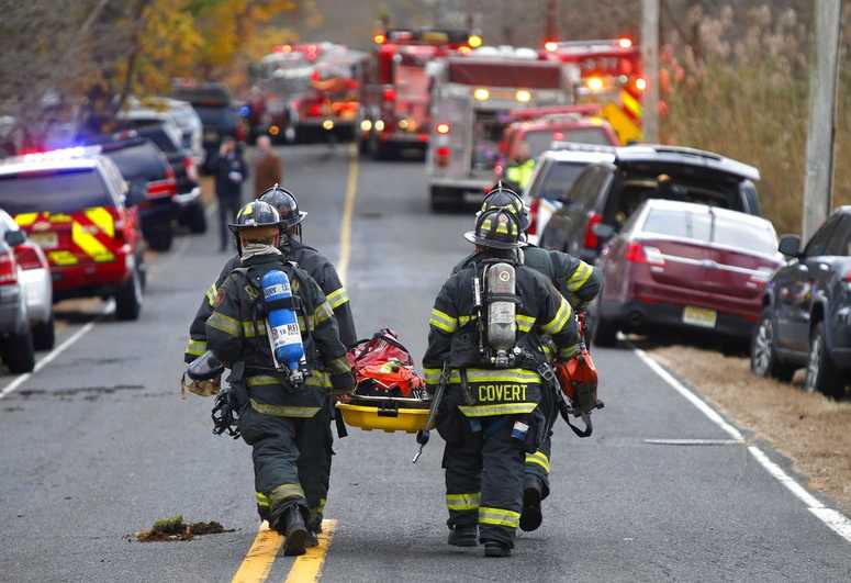 Firefighters carry a stretcher to the scene of fatal Colts Neck fire