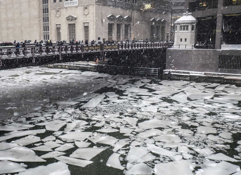 Pedestrians cross an icy Chicago River on Madison St. near the Civic Opera House in Chicago, Monday, Jan. 28, 2019. Chicago snow