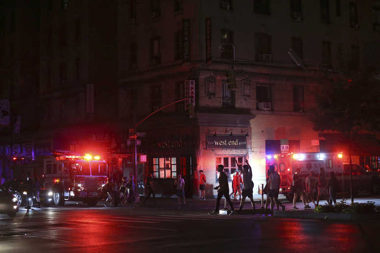 Pedestrians cross the street near emergency response vehicles at 50th Street and 8th Avenue during a power outage, Saturday, July 13, 2019, in New York. Blackout NYC AP